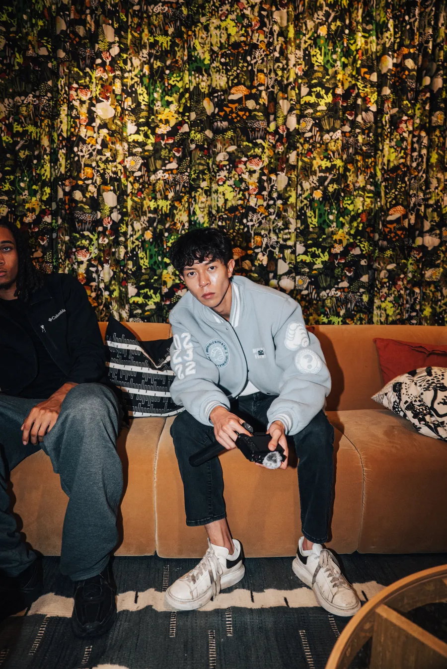 Two guests on a bench in front of a living wall
