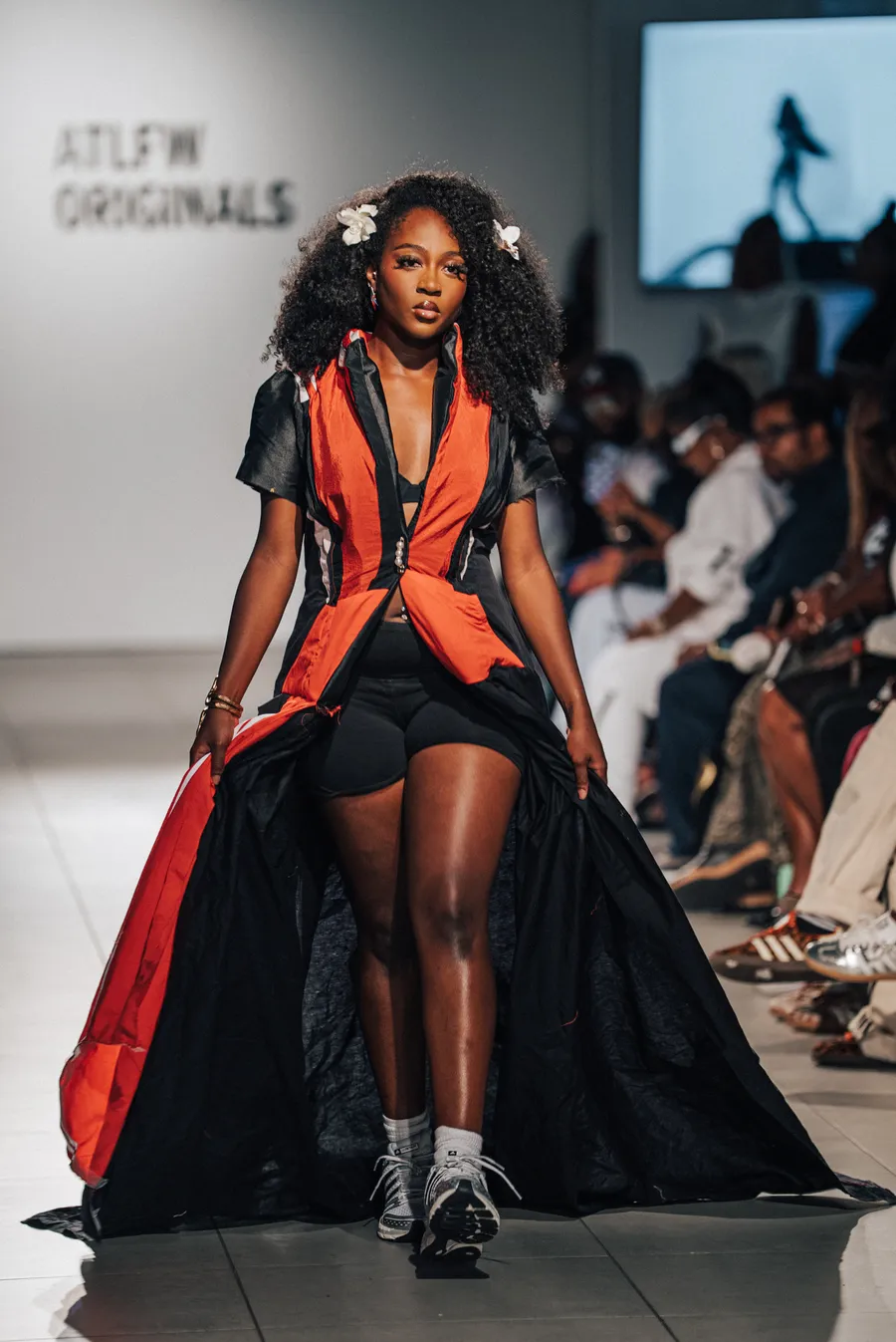 Model in a red and black cape gown on the runway