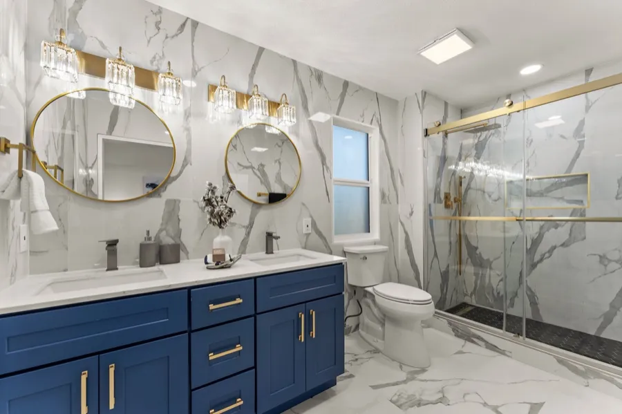 Bathroom remodel with navy double vanity and brass fixtures