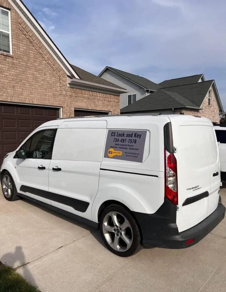 CS Lock and Key service van parked in the driveway of a brick home