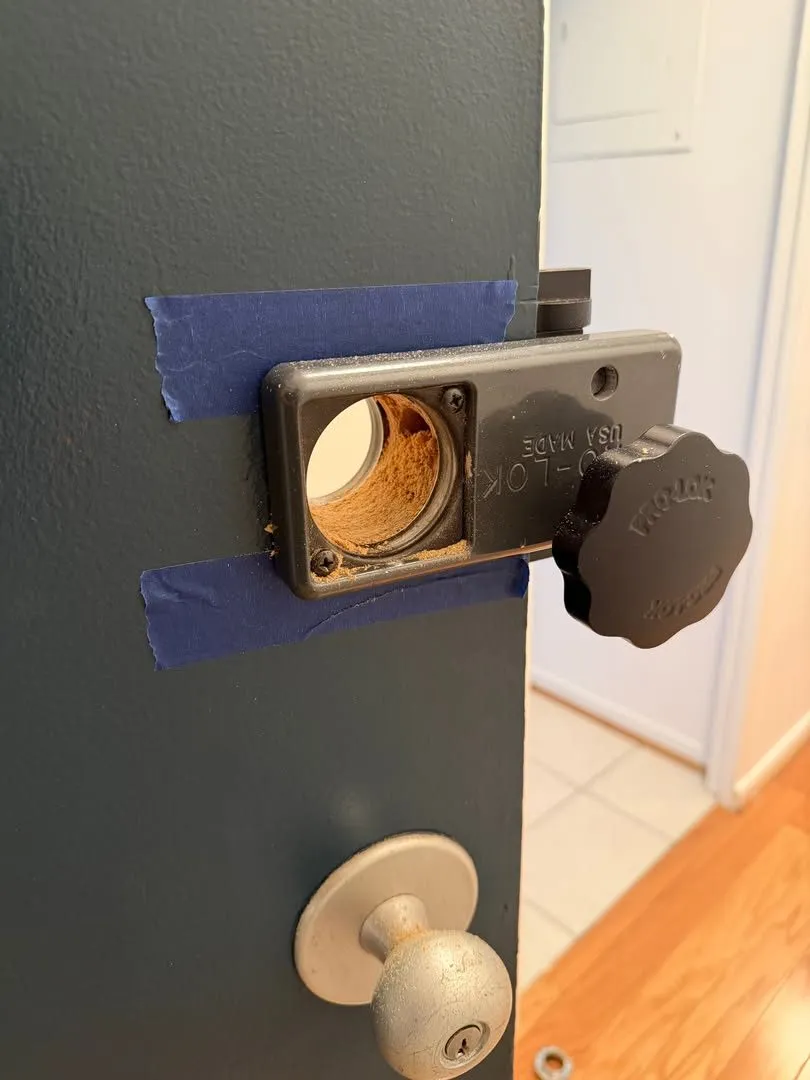 Deadbolt drilling jig clamped to a door edge