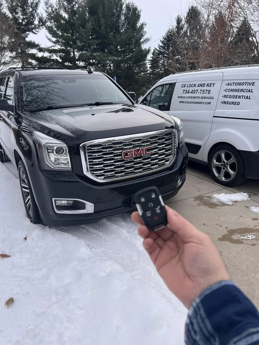 Smart key for a black GMC Yukon in the snow, with the CS Lock and Key van