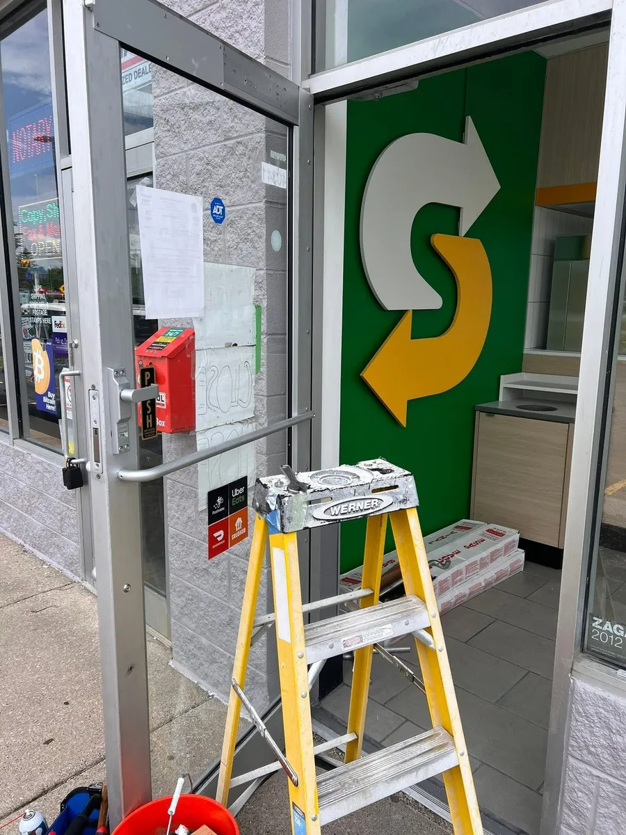 Ladder set up for door hardware work at a restaurant entrance
