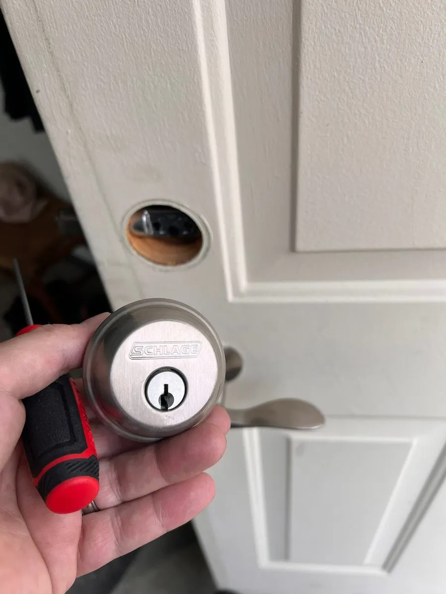 Deadbolt cylinder held beside a white door