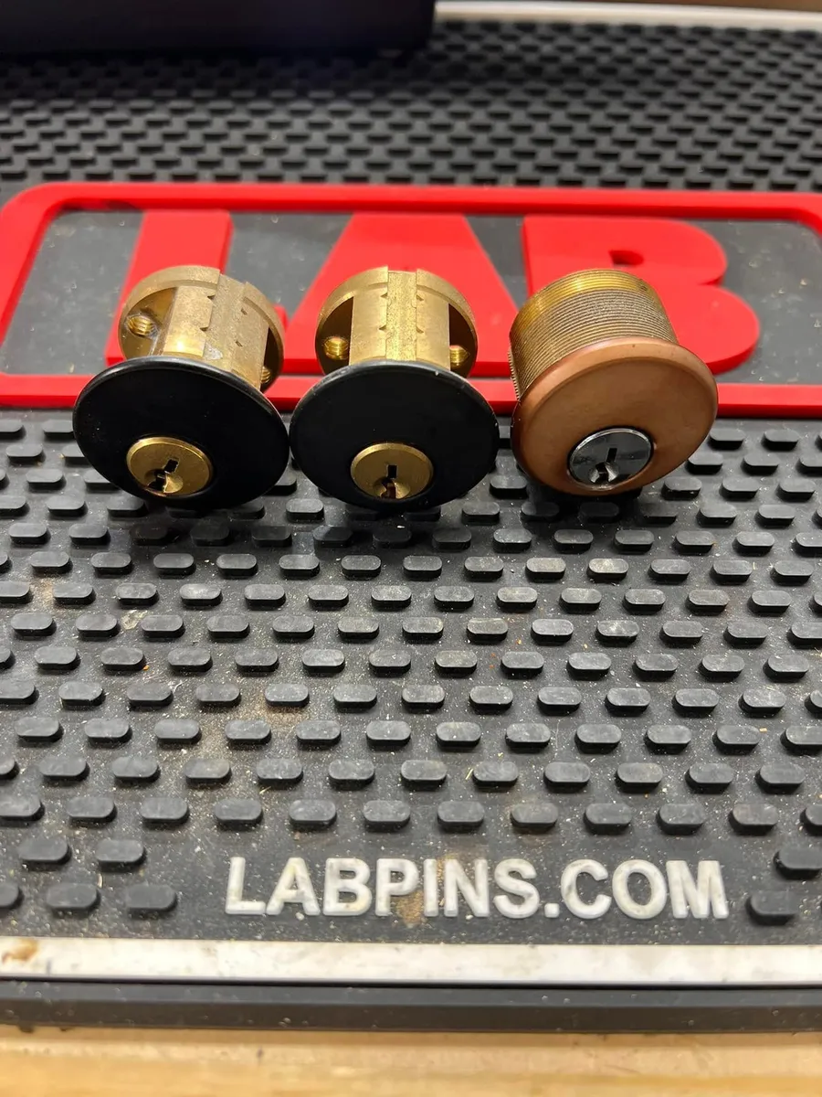 Three lock cylinders on a locksmith work mat