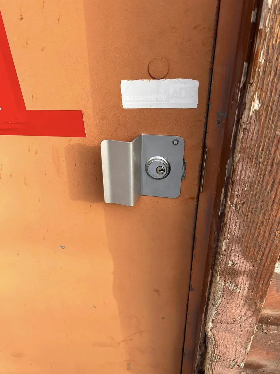 Keyed lock with a latch guard on a steel door