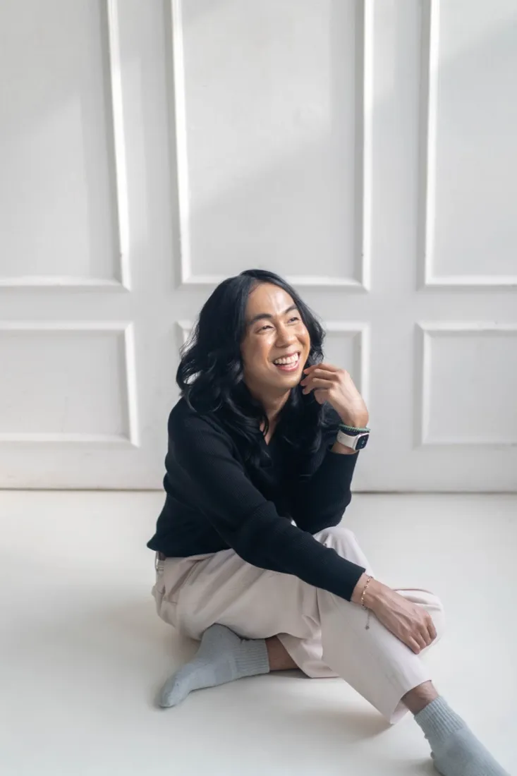Job Galido sitting on the floor, laughing