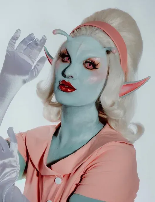 Blue alien character makeup with sculpted ears and a platinum wig