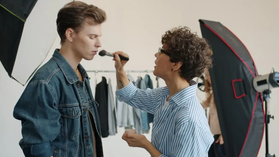 Artist grooming talent beside a softbox on a location shoot
