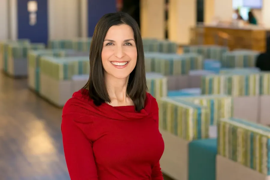 Corporate headshot of a woman in a red top in a modern office