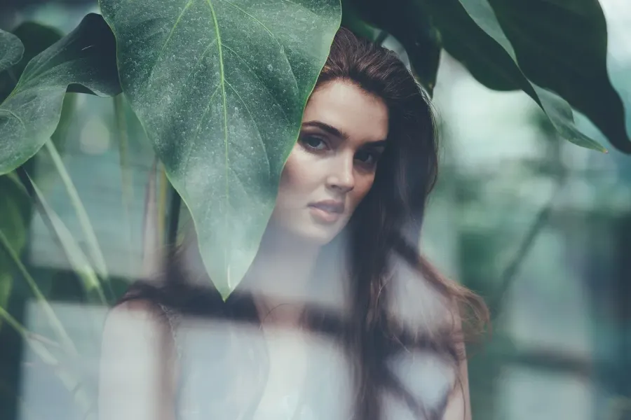 Editorial beauty portrait photographed through glass and leaves