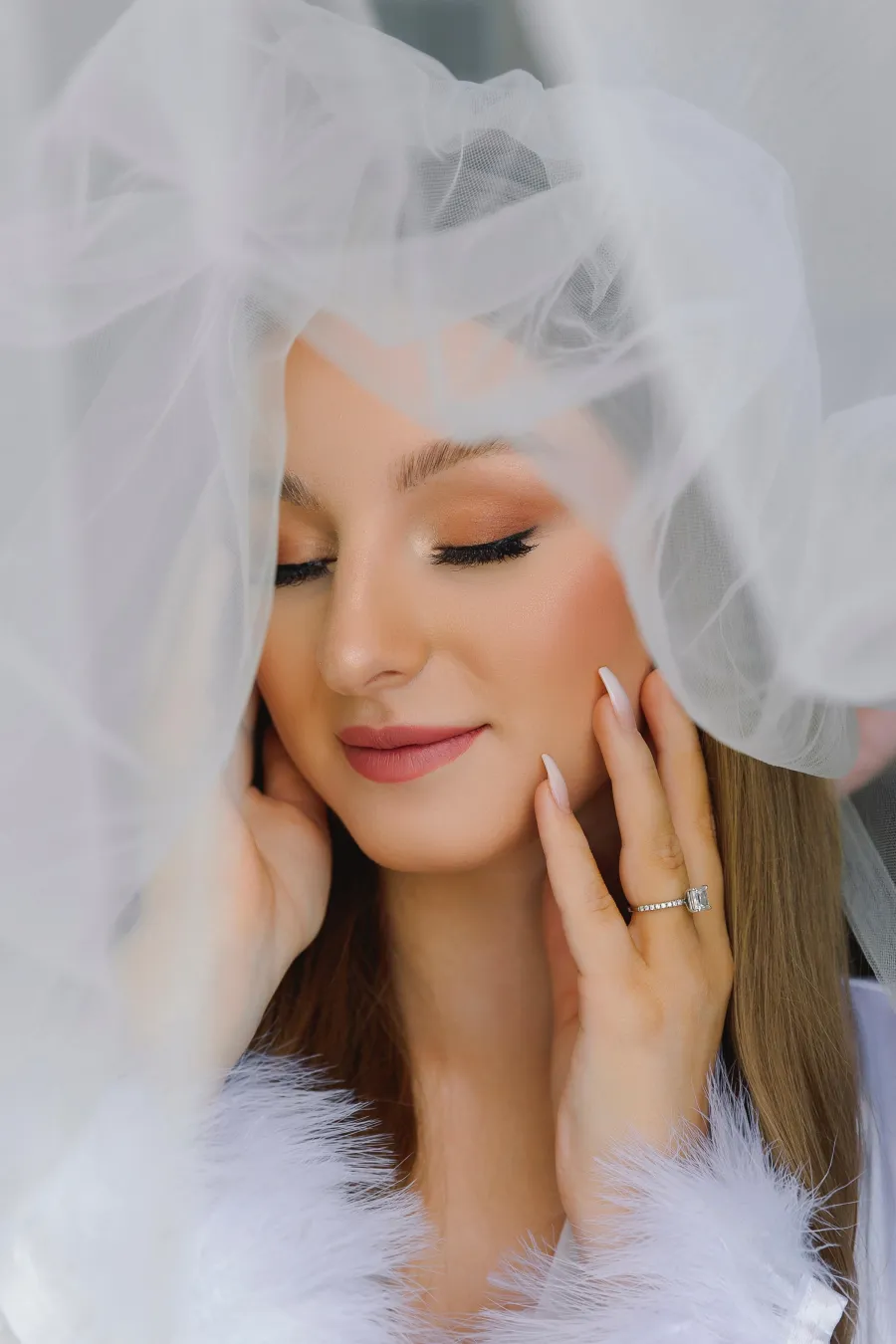 Bride with glowing skin and soft lashes framed by her veil