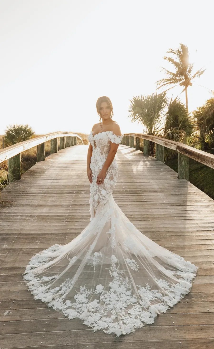 Bride in a lace mermaid gown walking a boardwalk at the beach
