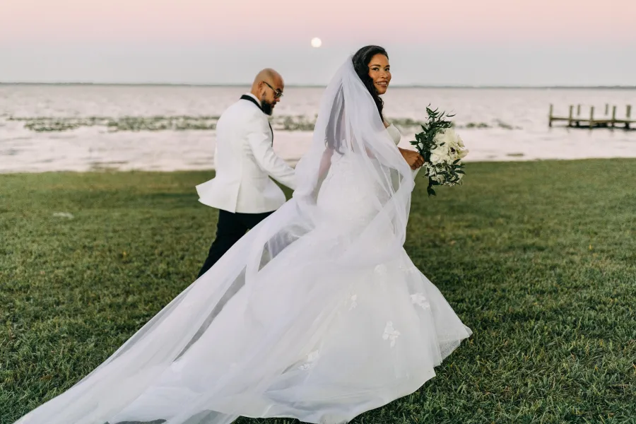 Bride's cathedral veil catching the wind on a Tampa Bay waterfront lawn
