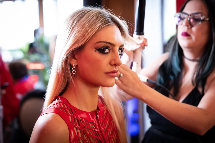 Makeup artist applying glam to a guest inside a branded activation lounge