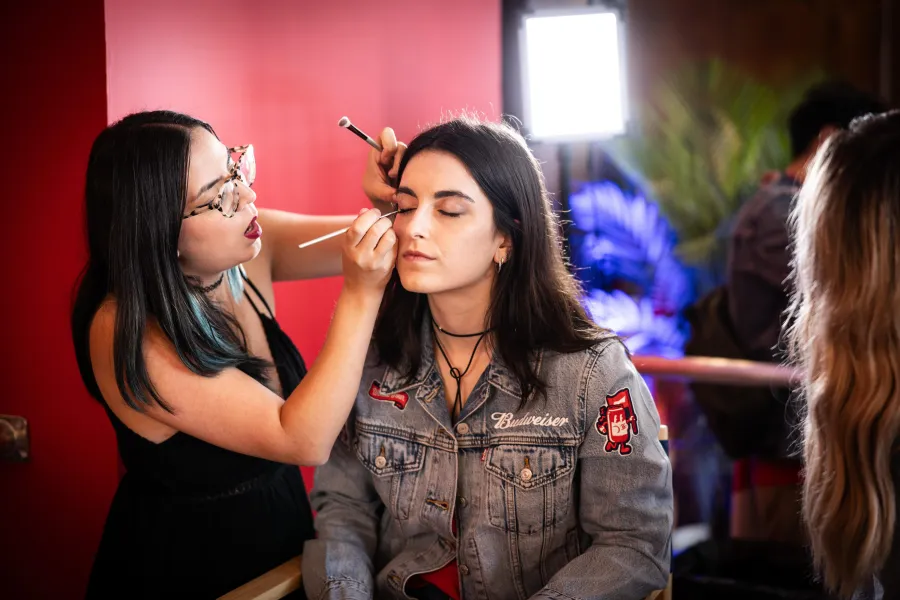 Makeup artist working on a guest in a Budweiser denim jacket