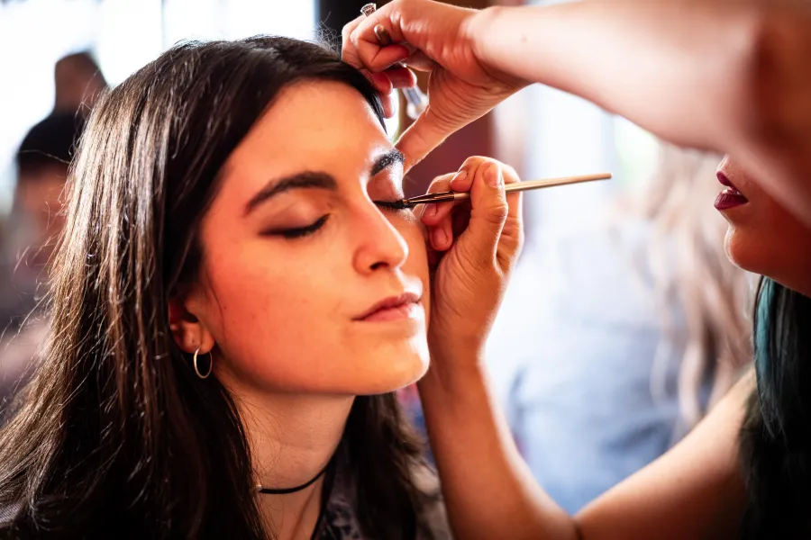 Artist lining a guest&rsquo;s eyes at a brand activation glam station