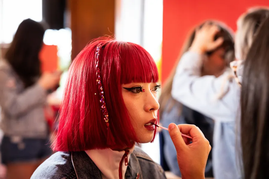 Model with a red bob touching up her lip colour at the Budweiser activation