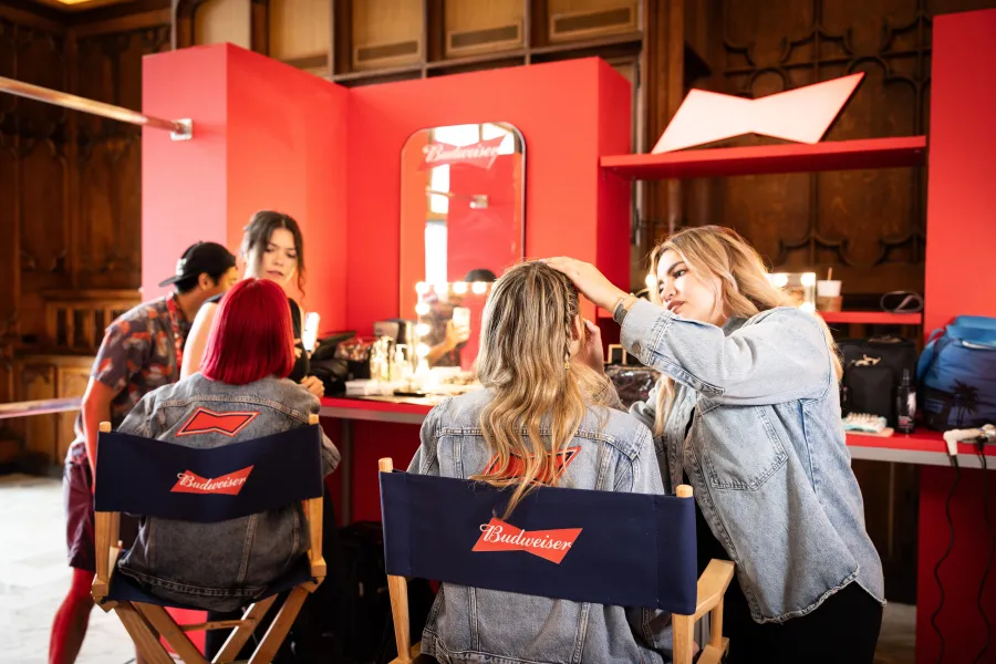 Two guests in branded director's chairs being styled at red vanity stations