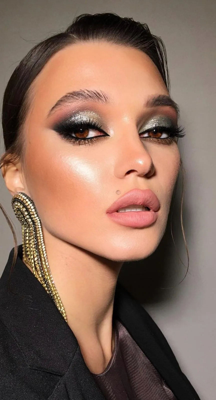 Event guest with sculpted evening makeup and sleek dark hair before a black tie gala