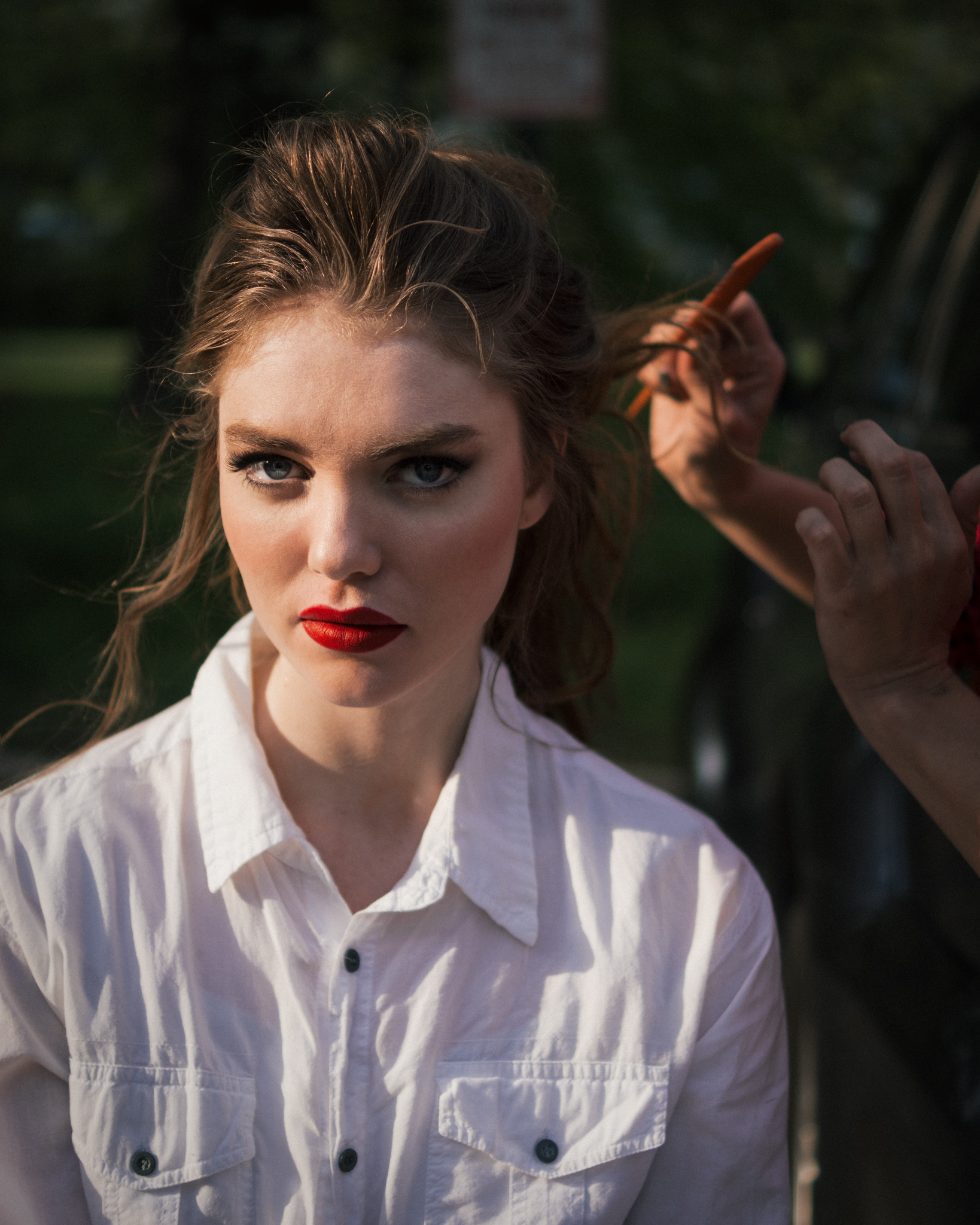 Hair stylist's hands adjusting a model's hair between frames on an editorial set