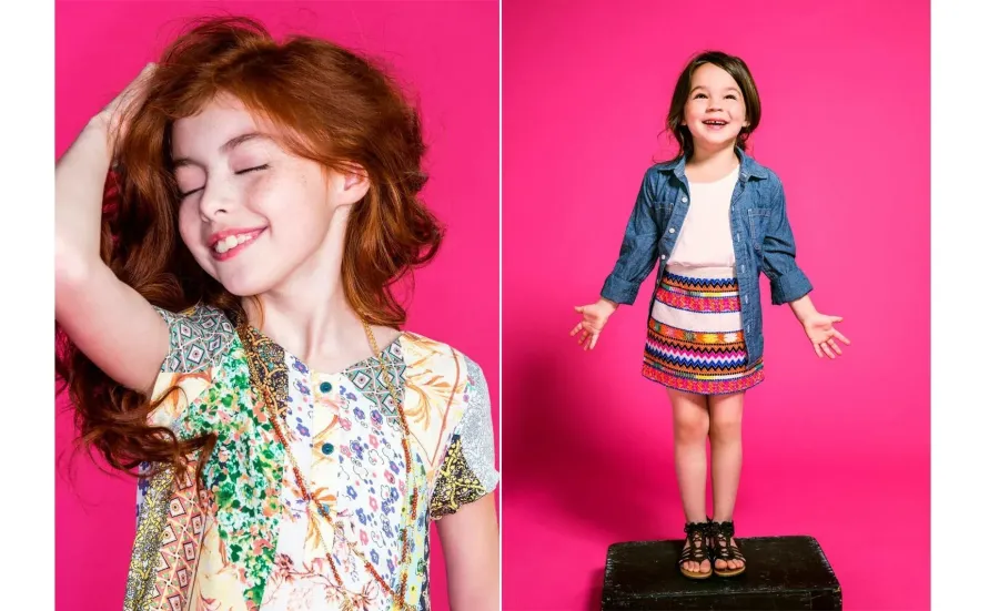 Two young girls modelling patterned kids clothing against a pink studio backdrop