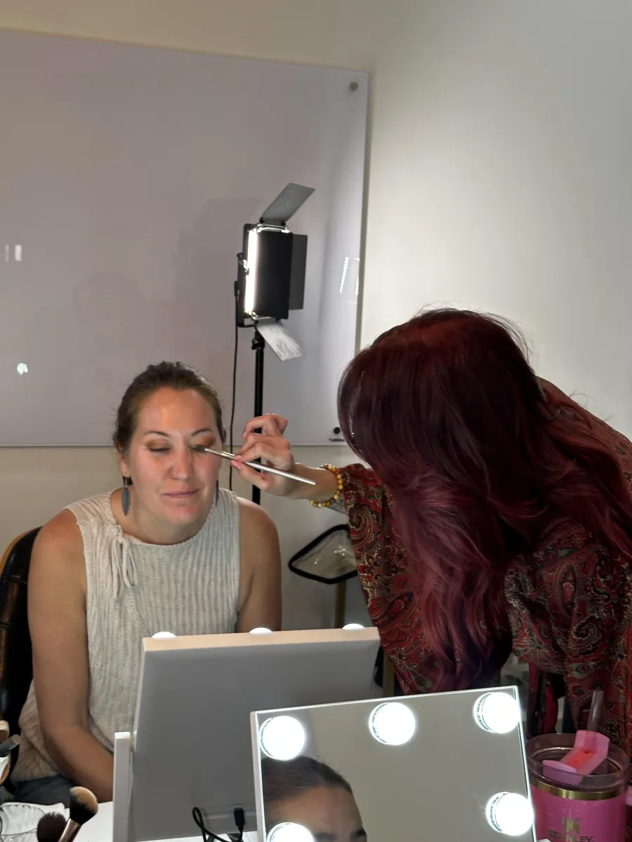 Paula Heckenast applying makeup to a client at a lighted vanity during a private lesson