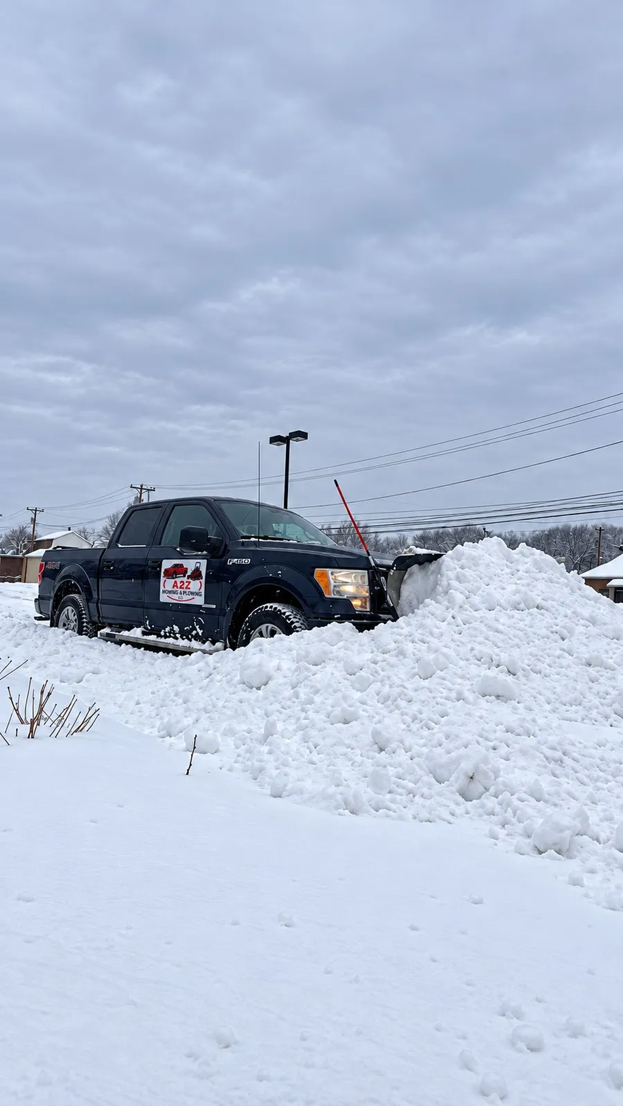An A2Z plow truck beside the snow pile it pushed up clearing a lot