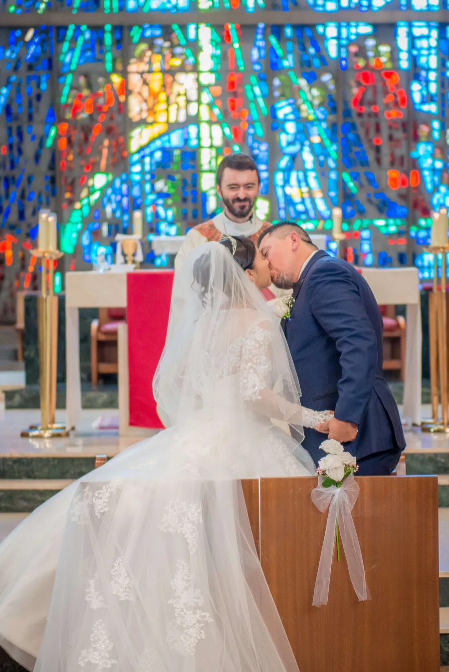 Primer beso en una ceremonia religiosa frente a vitrales
