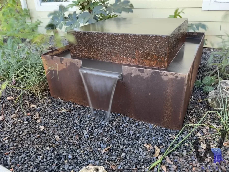 Corten steel water feature spilling into a basin