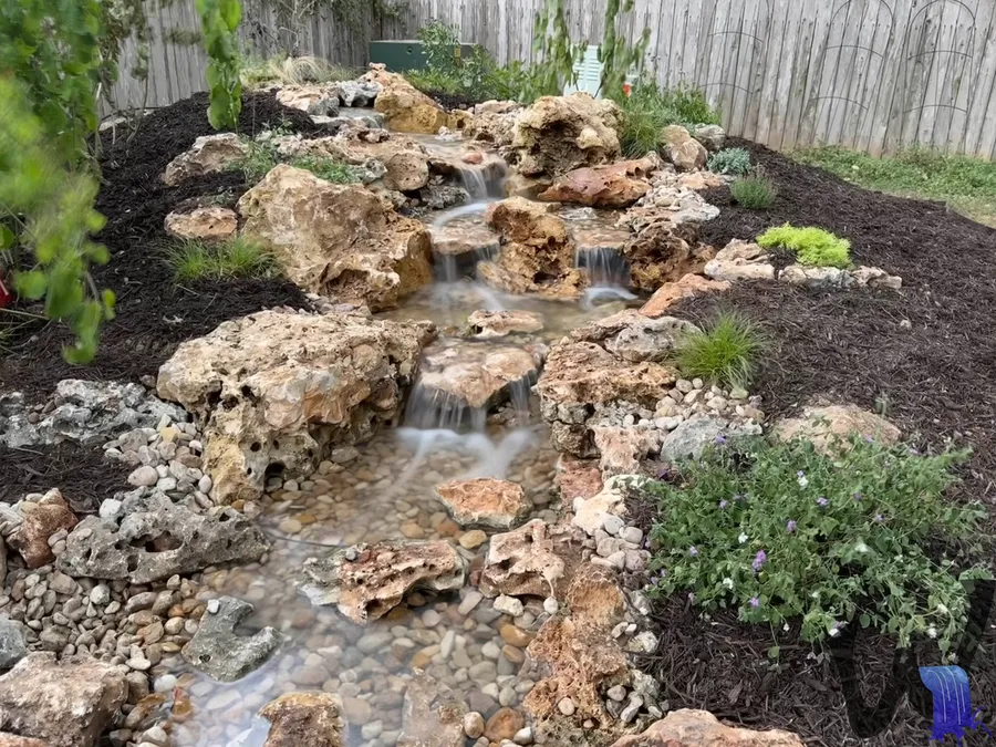 Pondless waterfall tucked into a planted bed