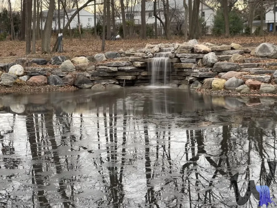 Pond edge with a waterfall and rock border