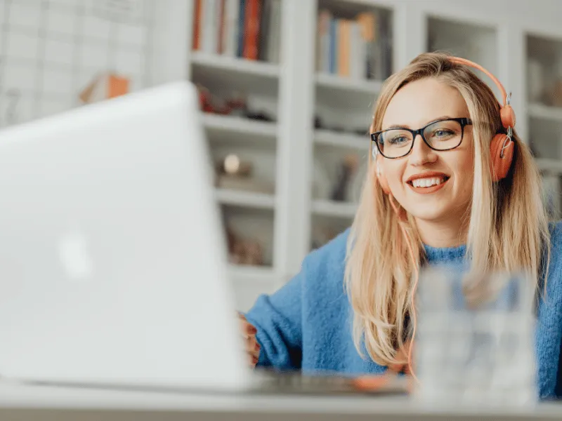 A smiling teacher in headphones joining a free Teacher Transition live workshop from her laptop