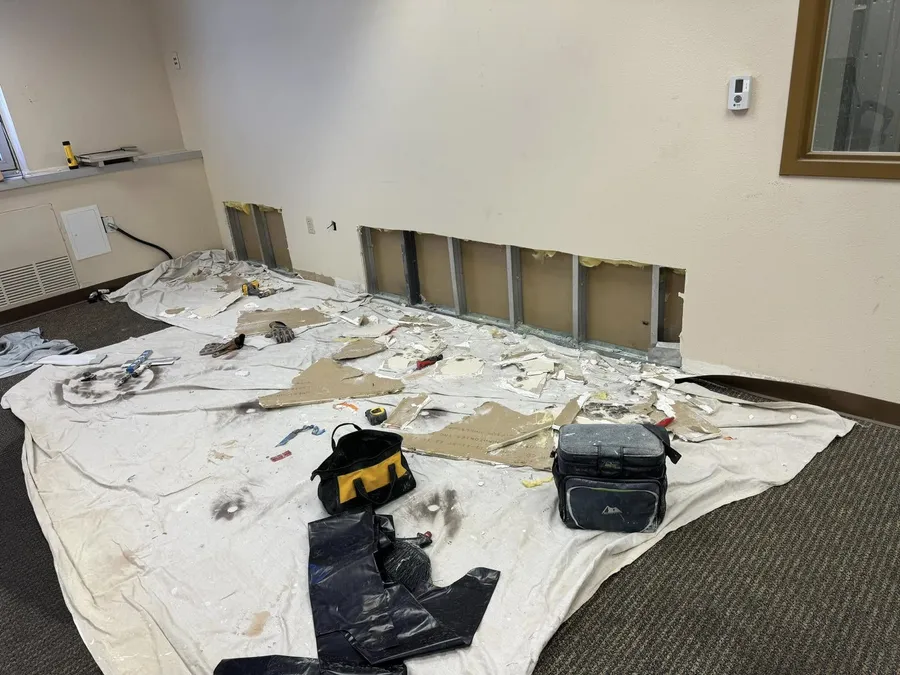Lower wall opened up for drywall repair in an office