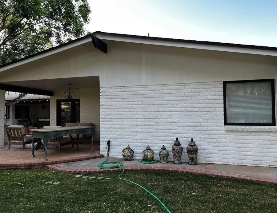 White painted brick home with a covered patio
