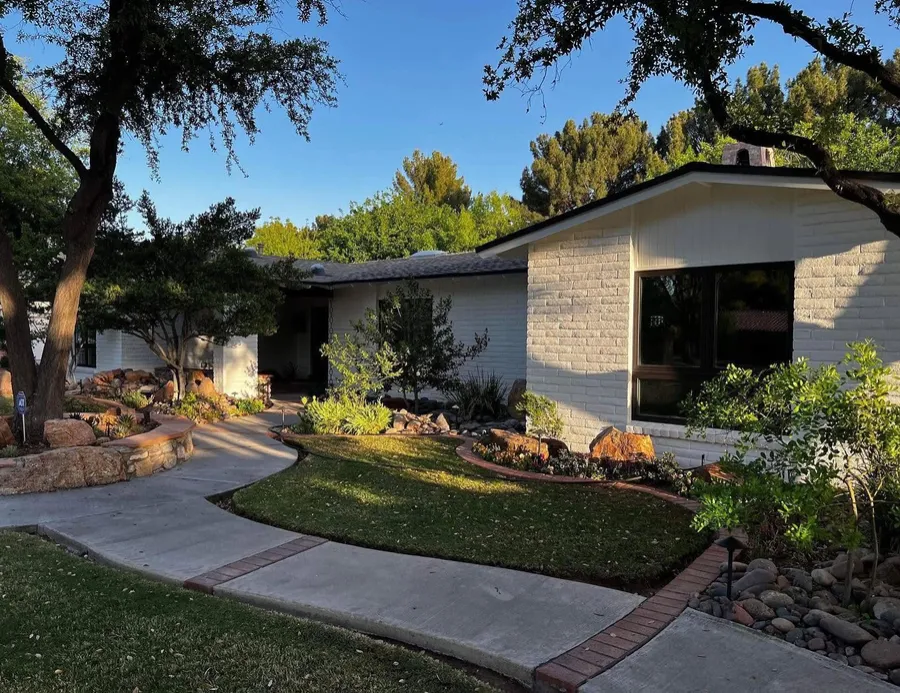 Single-story white brick home with a landscaped front yard