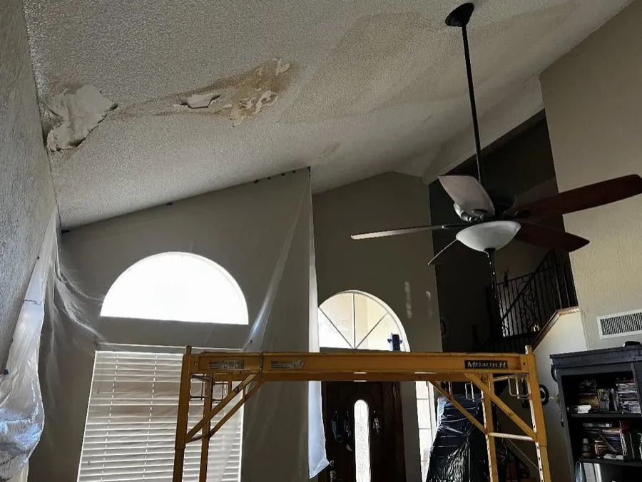Popcorn ceiling being scraped in a living room with scaffolding