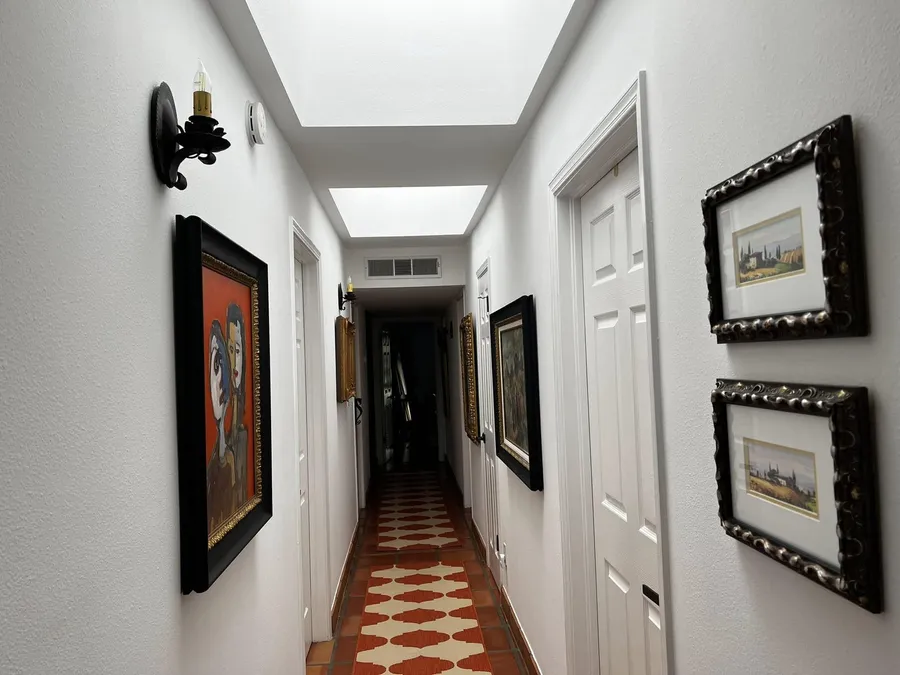 Bright white hallway with skylights and framed art