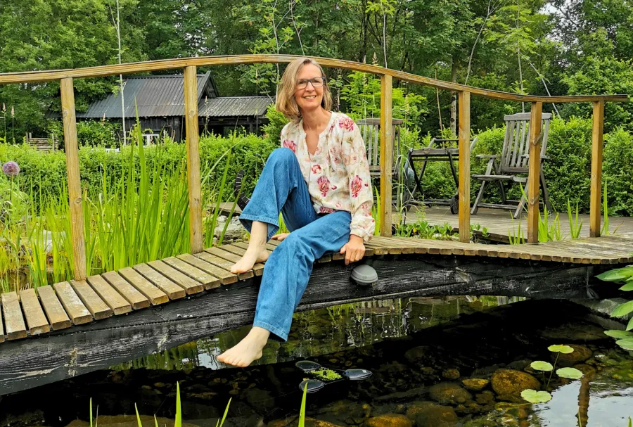 Christina Waardal sitter avslappet på en bro i hagen.