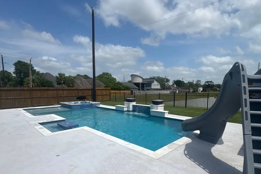 Clean, sparkling backyard pool with slide, serviced by The Spa Guy