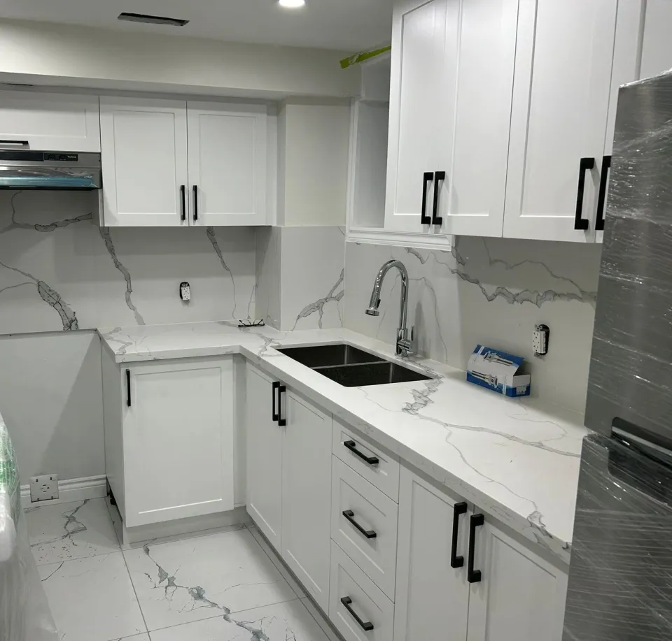 White kitchen with marble-look quartz counters and full-height backsplash