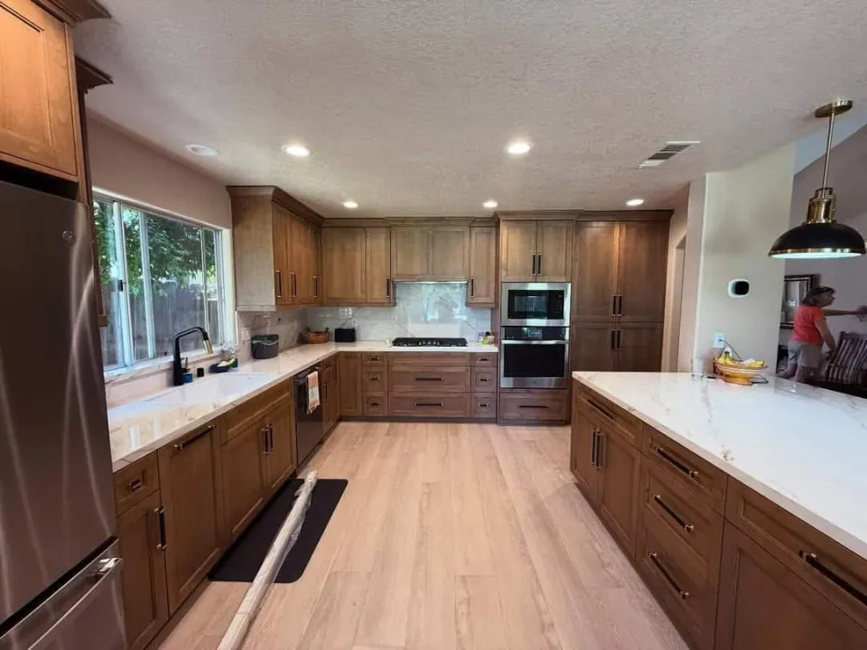 Warm wood kitchen cabinetry with white quartz counters and light plank flooring