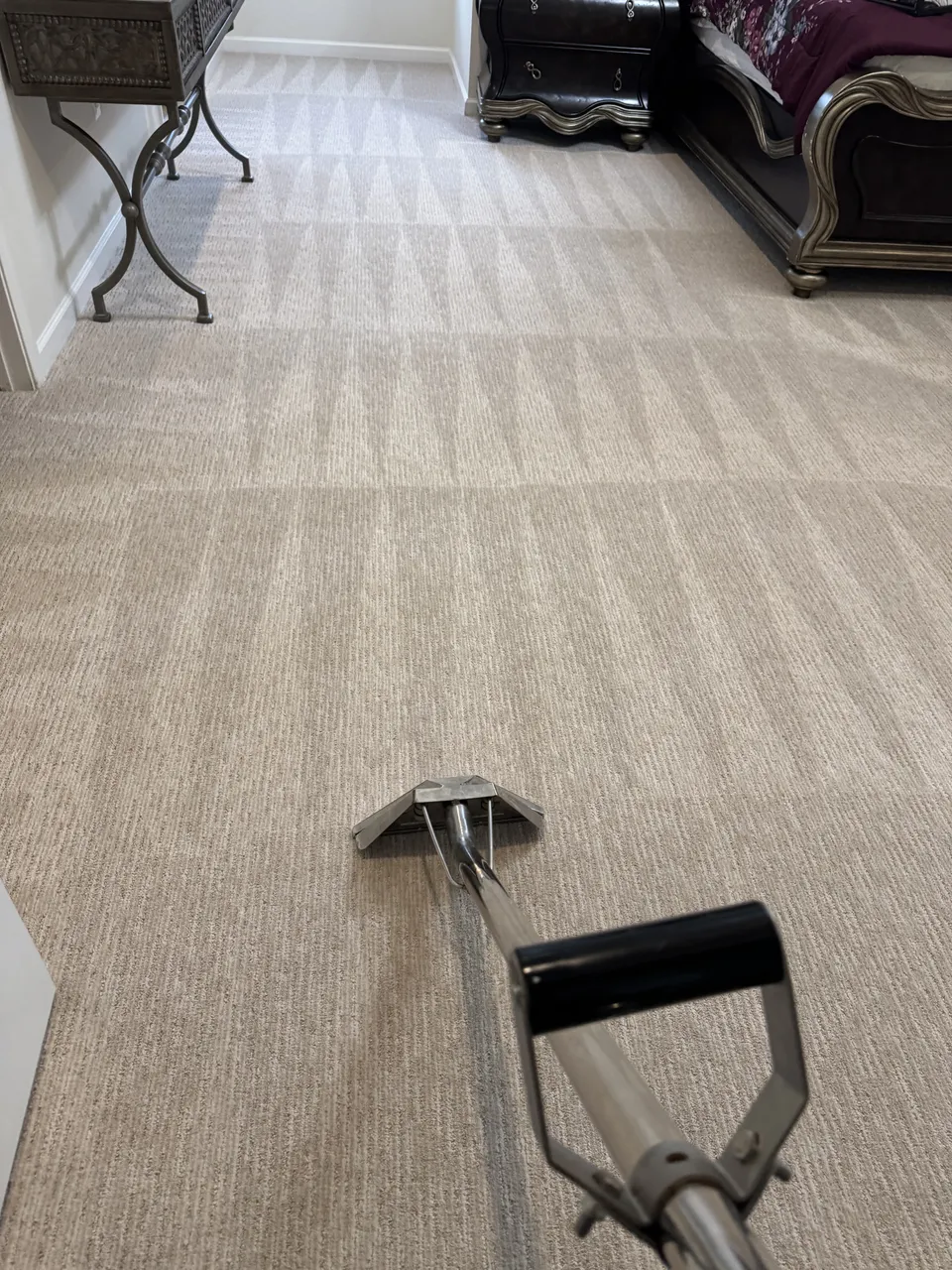 Room carpet being cleaned with a cleaning wand by Ricco Carpet Cleaning.