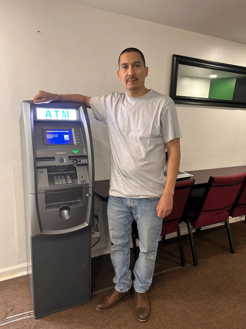 A business owner standing next to a newly installed ATM inside his restaurant