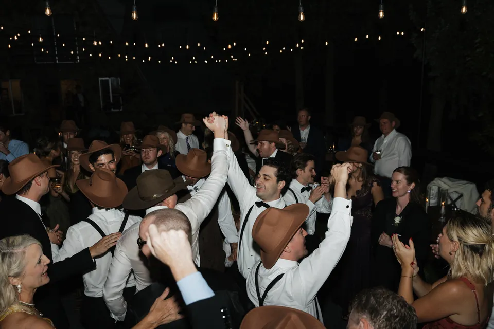 Wedding guests dancing together beneath string lights at Stone Crossing.