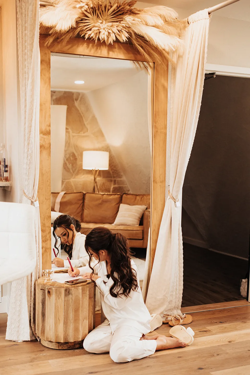 A bride writing beside the large mirror and gold sofa in the bridal suite.