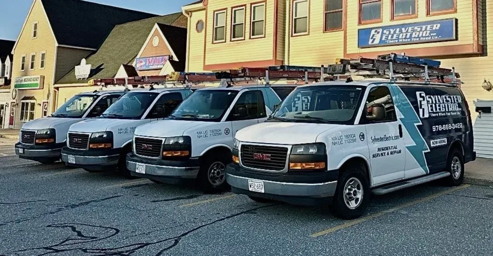 Branded Sylvester Electric service vans outside the company building