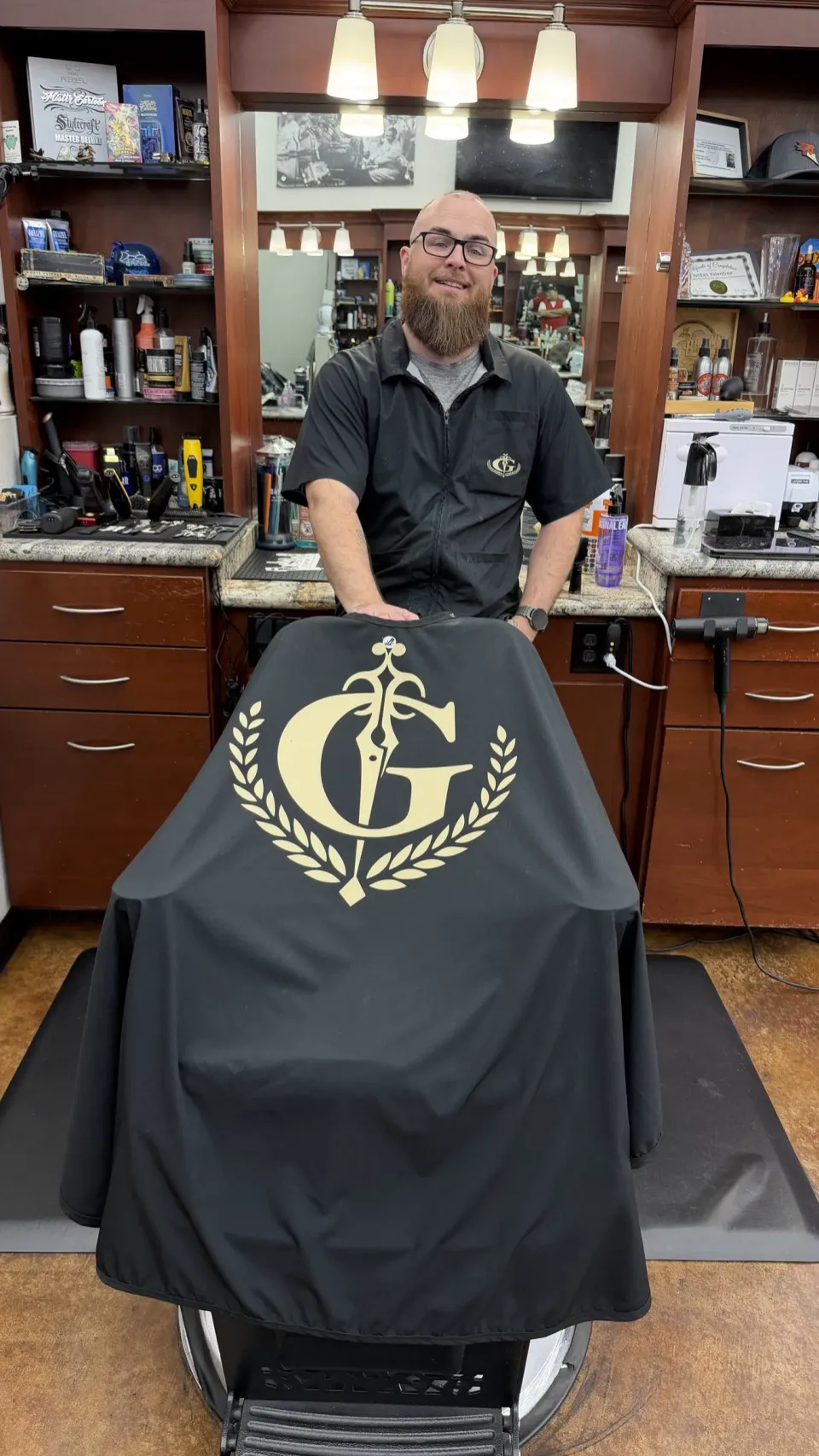Jordan holding the black Gentlemen's Cutz cape with the gold crest