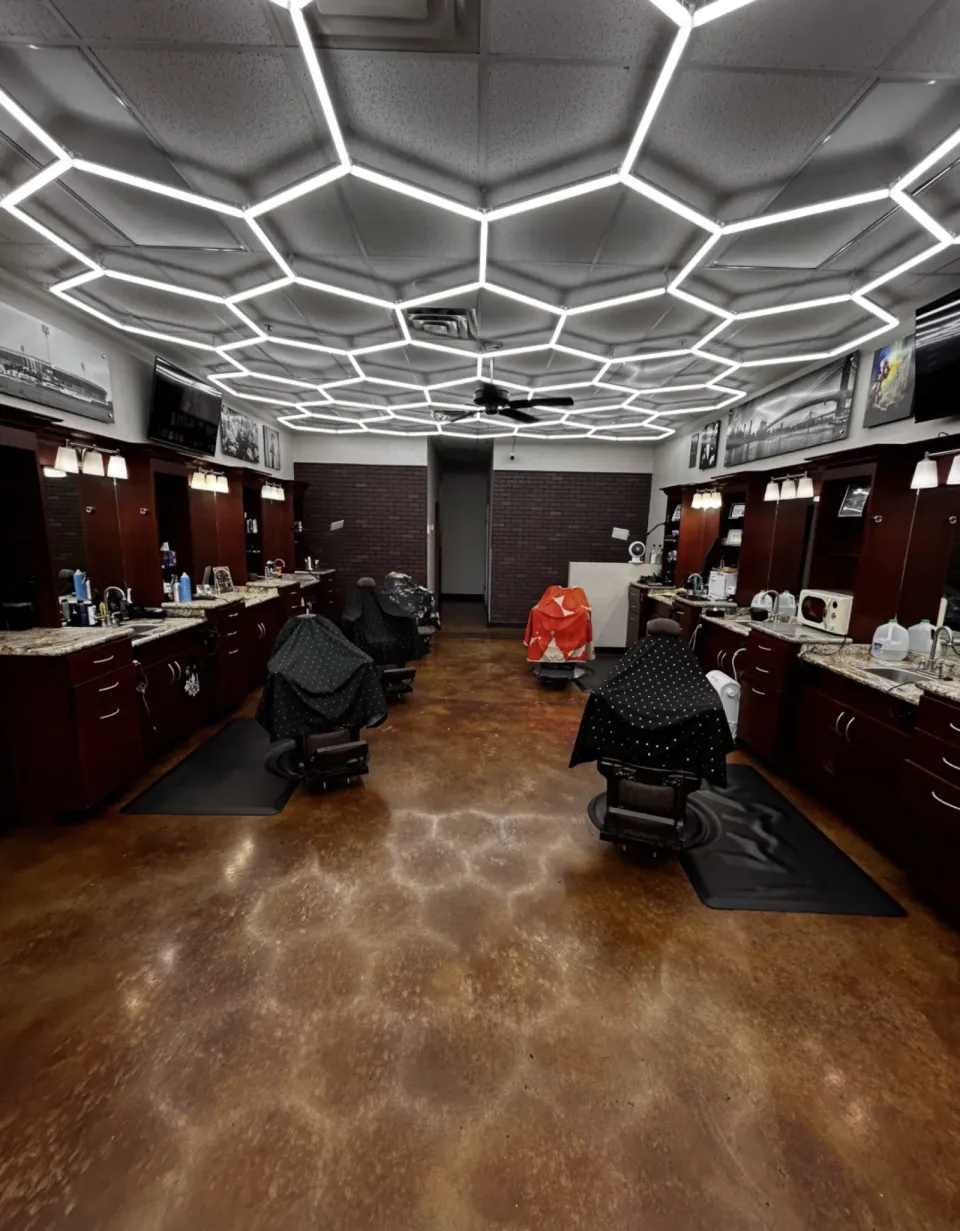The inside of Gentlemen's Cutz under its hexagon light ceiling, with barber chairs on both sides