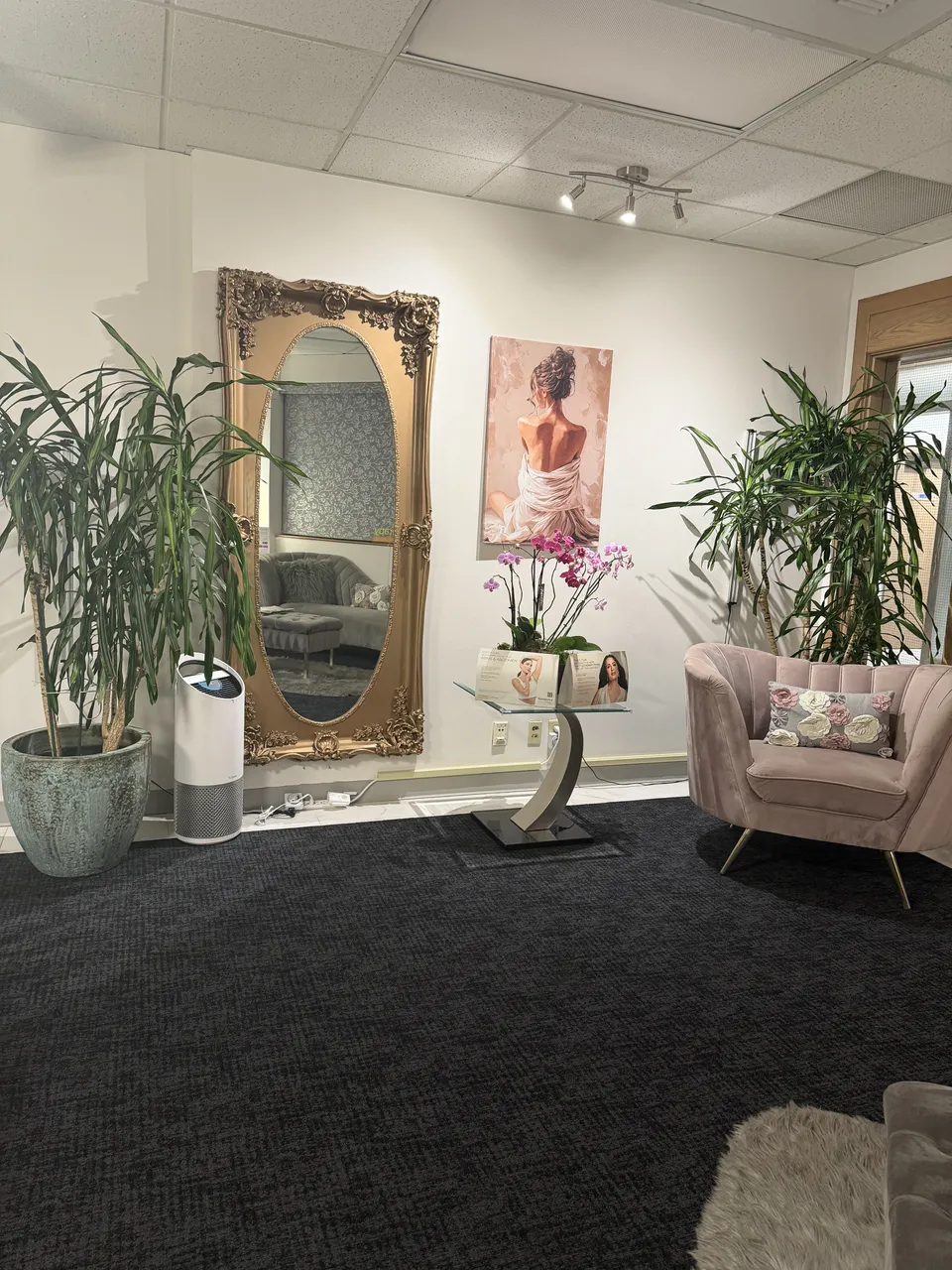 Reception seating with a gold-framed mirror, orchids and plants.
